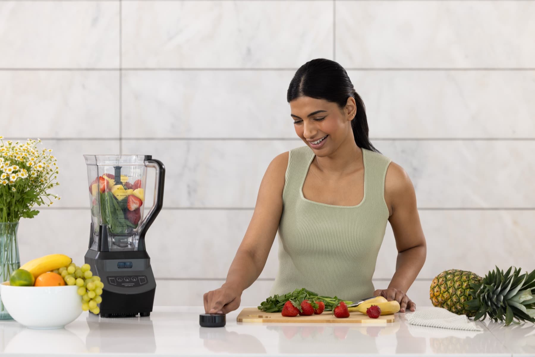 A smiling woman at a kitchen counter resting a fingertip on the Prysm iO scanner